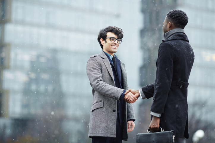 Implementing winter workplace safety tips help keep these two businessmen shaking hands safe.