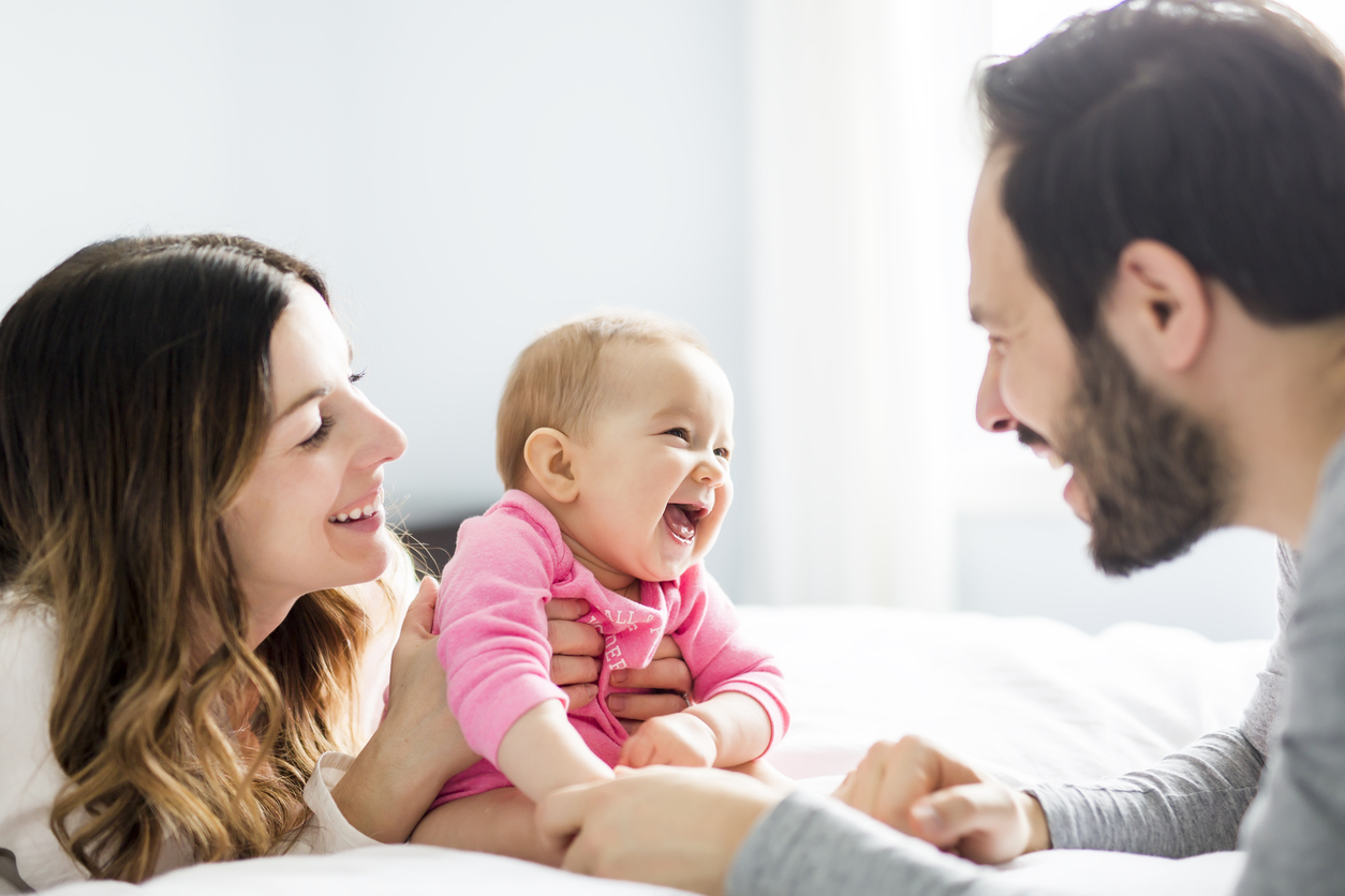 Two new parents with their baby while on maternity and paternity leave from their employers.