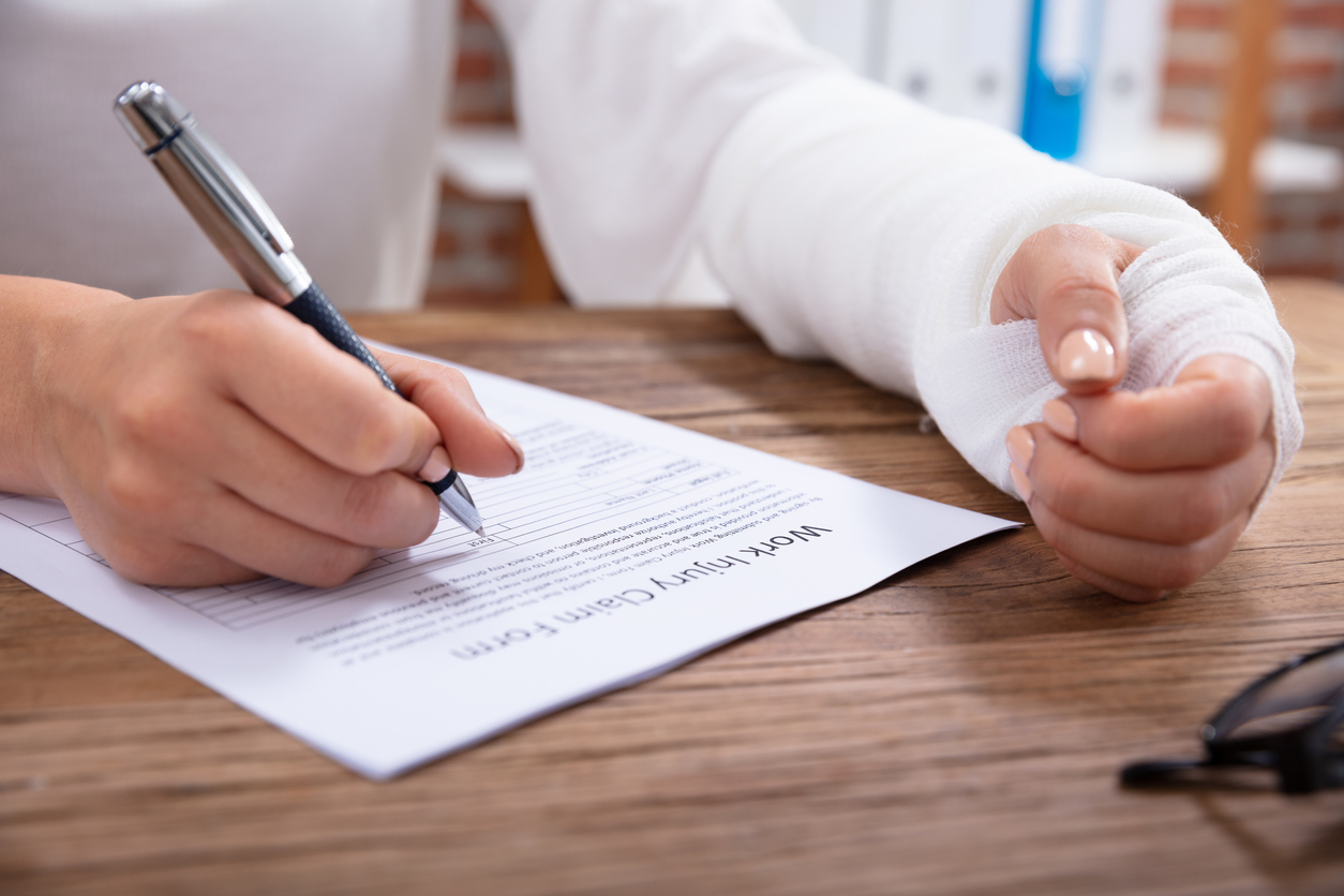 A woman filling out a work injury form for a Tennessee employer with workers’ compensation insurance.