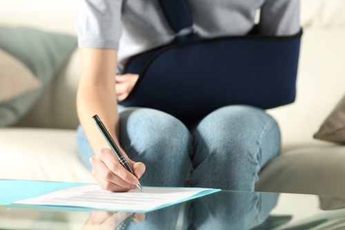 A woman with an injured arm signing up for voluntary disability insurance.